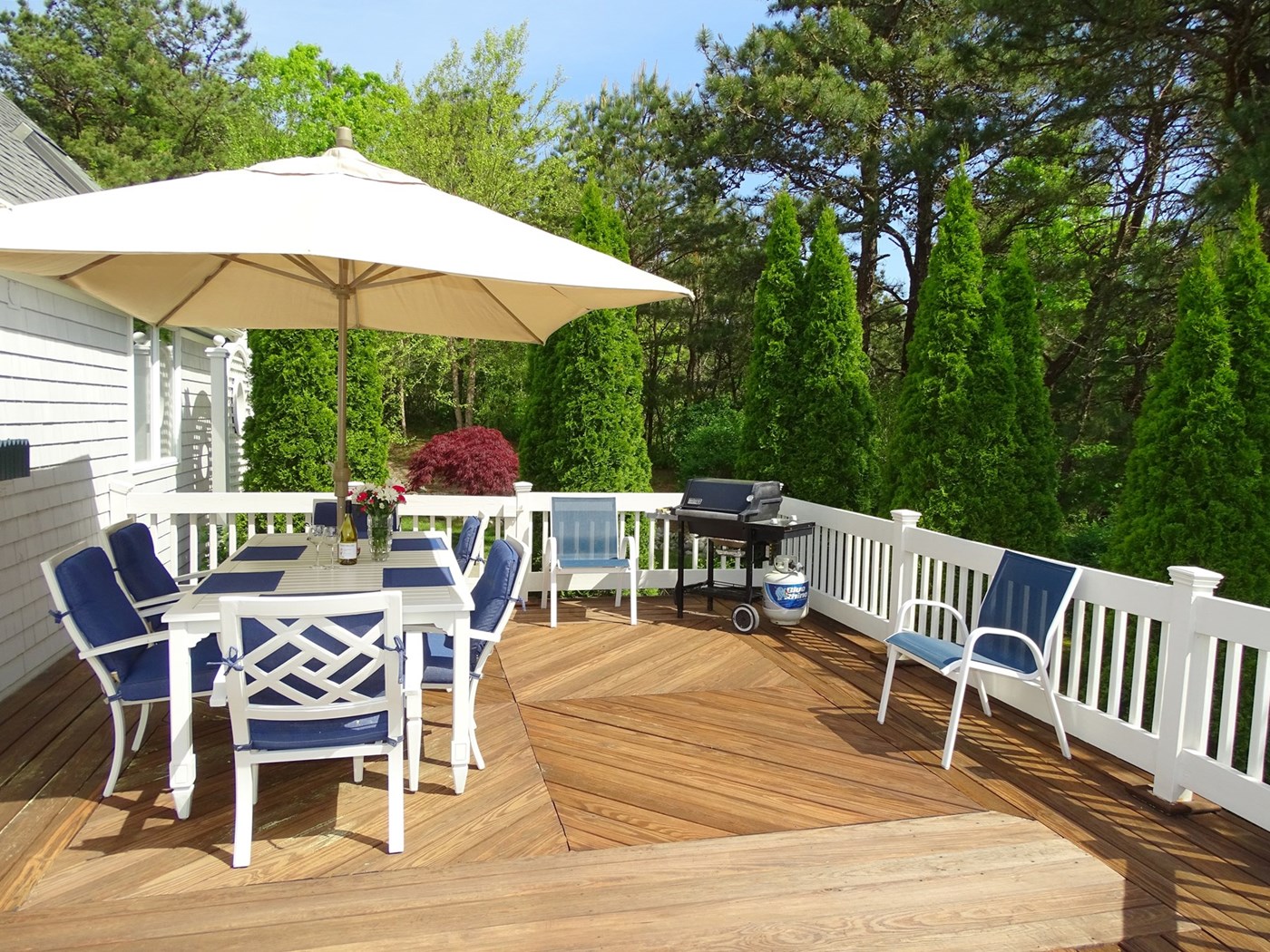 View of back of house, outdoor shower, patio, gardens