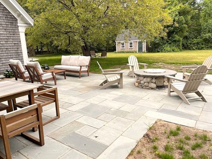 Brewster Cape Cod vacation rental - spacious patio provides several options for outdoor living.  Note the umbrella shaded dining table and fire pit seating.