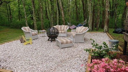 South Eastham Min to Bike Path Cape Cod vacation rental - Firepit area surrounded by white wicker furniture & mature trees