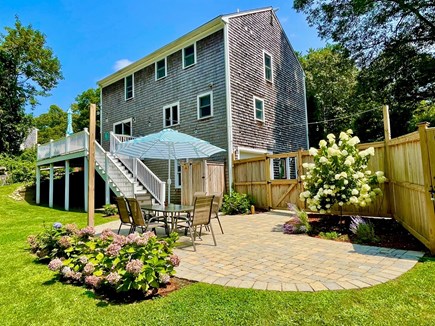 Yarmouth Port Cape Cod vacation rental - Backyard stone patio with dining area and deck with lounge area