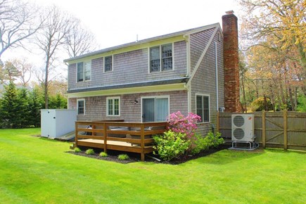 Yarmouth Port Cape Cod vacation rental - Back of the home with large deck, outdoor shower and green grass.