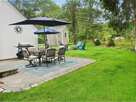 Harwich Cape Cod vacation rental - Backyard with patio, seating, grill and firepit.