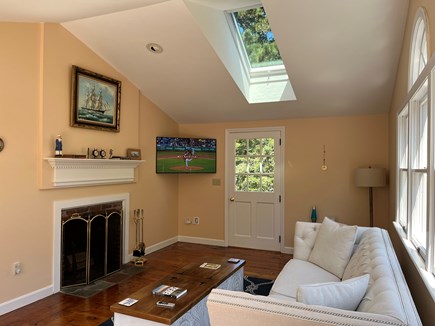 Harwich Port Cape Cod vacation rental - Living room with fireplace, skylight, and flat screen TV.