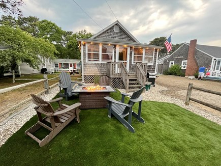 Dennis Port Cape Cod vacation rental - Turf lawn, propane fire table, Adirondack chairs, sunny yard