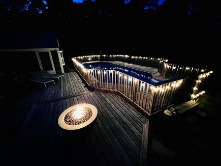 Brewster Cape Cod vacation rental - Private heated pool at night with lights on and fire pit.