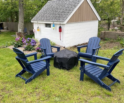 Dennisport Cape Cod vacation rental - Backyard with fire pit and Adirondack chairs.