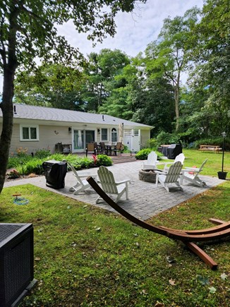 Cotuit, Barnstable Cape Cod vacation rental - Back yard with deck and dinner seating; fire pit and hammock.