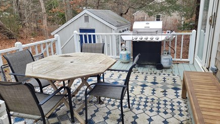 Centerville Cape Cod vacation rental - Deck overlooking yard - gas grill, dining table, & extra seating.