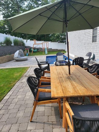 Mashpee Manor Pool House Cape Cod vacation rental - Pool area with firepit, seating area and a play set for children.