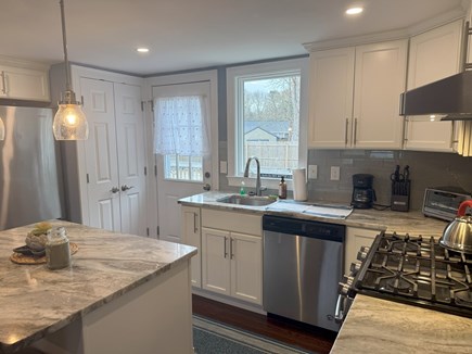 West Yarmouth Cape Cod vacation rental - Kitchen area with back door leading out to deck & fenced in yard