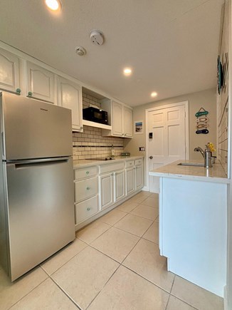 West Dennis Cape Cod vacation rental - Kitchen with stove top, full fridge, sink, micowave.