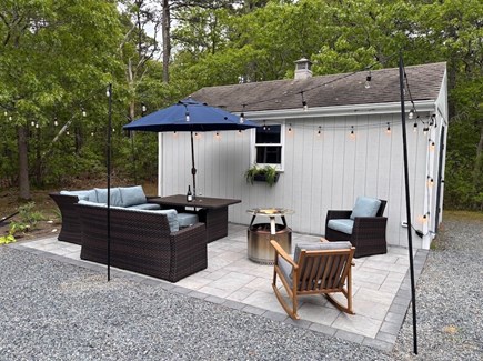 Eastham Getaway Cape Cod vacation rental - Outdoor patio lounge with string lights and fire pit