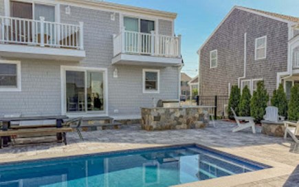 Sandwich Cape Cod vacation rental - View of the back of the home with the bar, picnic table, and fire pit