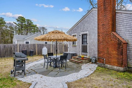 Dennis Port Cape Cod vacation rental - Side patio with a dining table and chairs and an umbrella.  Perfect for a gathering
