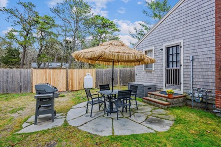 Dennis Port Cape Cod vacation rental - Side patio with a dining table and chairs and an umbrella.  Perfect for a gathering.