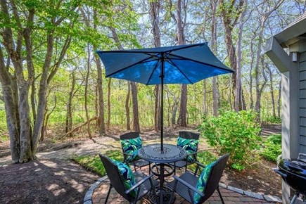 New Seabury, Mashpee Cape Cod vacation rental - Back patio with an outdoor dining table, offering a comfortable space for al fresco meals surrounded by nature and a peaceful outdoor setting.