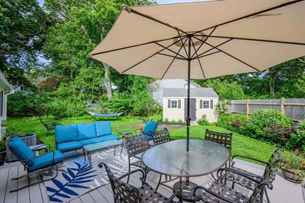 Hyannis Cape Cod vacation rental - Back patio featuring outdoor seating and a dining table, creating the perfect space for relaxing, gathering, and enjoying meals outdoors.