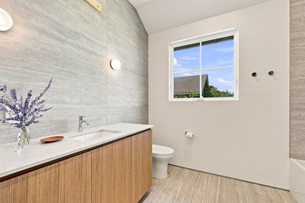 Orleans, Nauset Tide Cape Cod vacation rental - Modern bath with wood vanity, walk-in shower and sleek gray tile.