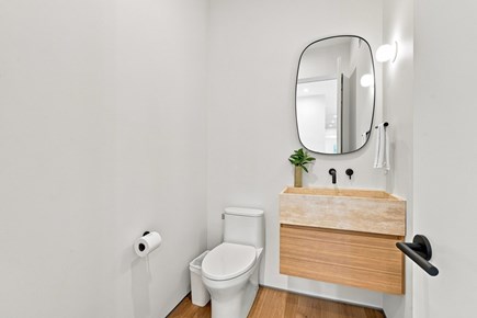 Orleans, Nauset Tide Cape Cod vacation rental - Minimal half bath with floating wood vanity and a rounded mirror