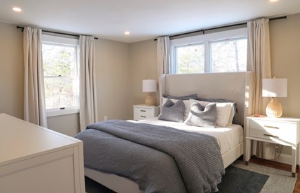 Eastham Cape Cod vacation rental - The primary bedroom features a queen bed, dresser, mirror, and TV
