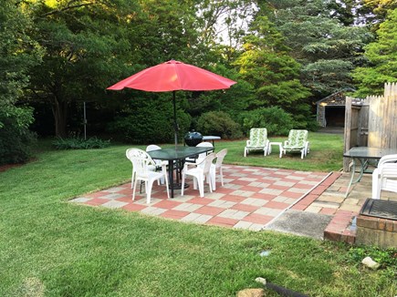 Hyannis Cape Cod vacation rental - Back yard Patio w/ Charcoal Grill and towering trees on the side.