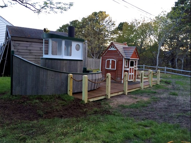 Backyard with a child's playhouse and climb-aboard tugboat
