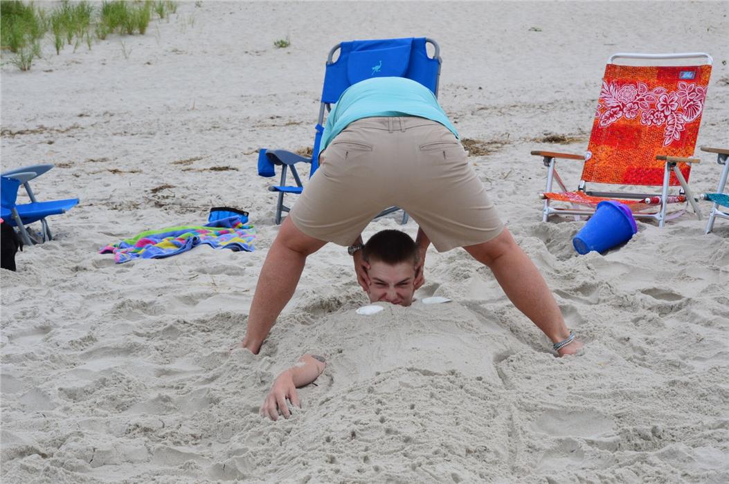 My sisters partner trying to pull my 19 year old son out of the sand by his head, we buried him and shaped it like a mermaid.