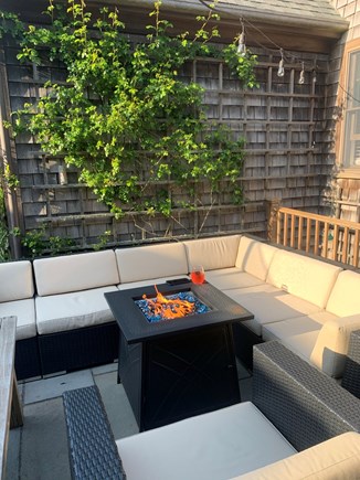 Mid-island Nantucket vacation rental - Seating area with table, gas fire pit, roses and string lights